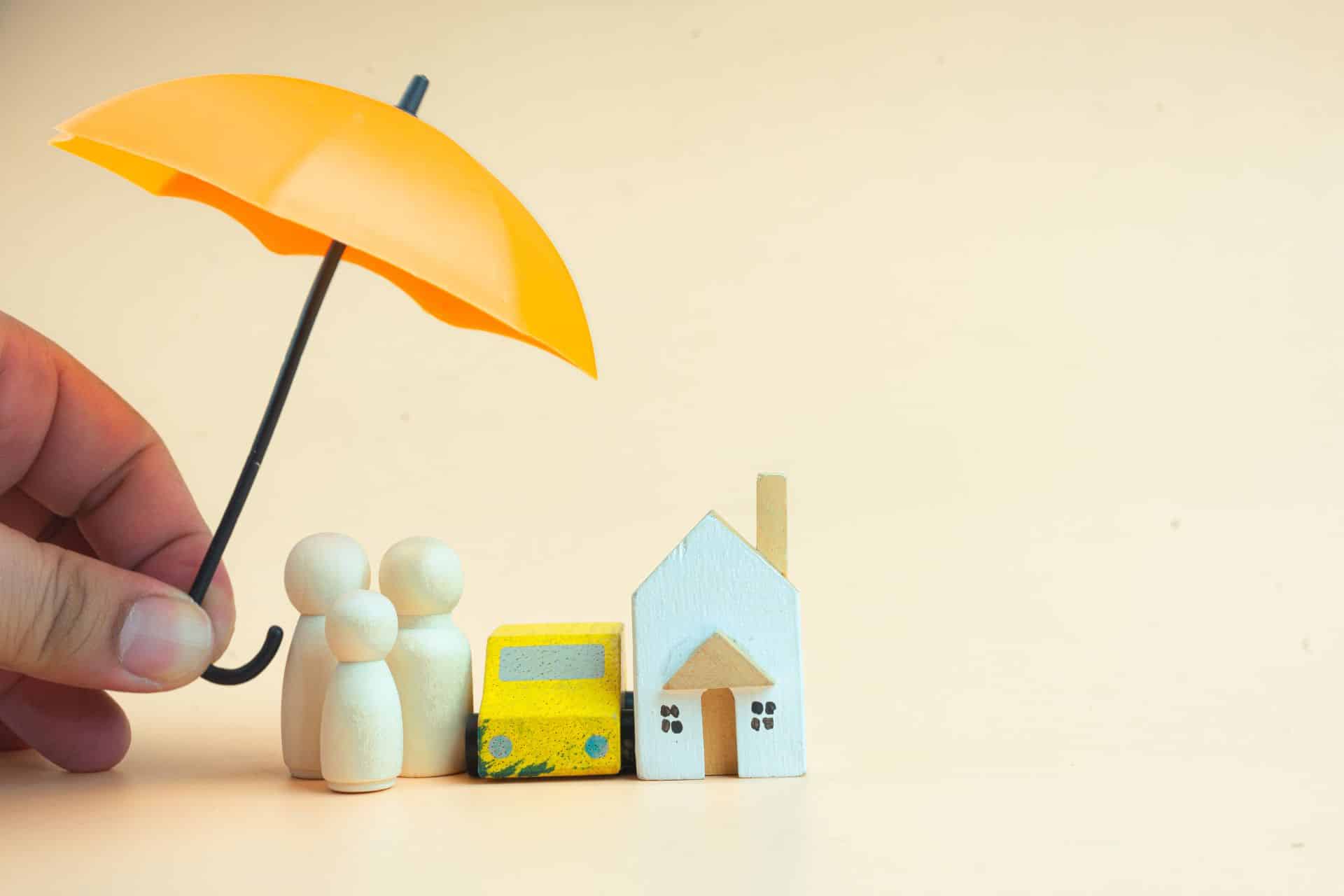 image of a umbrella over the top of model people and a model house. Symbolising financial protection.