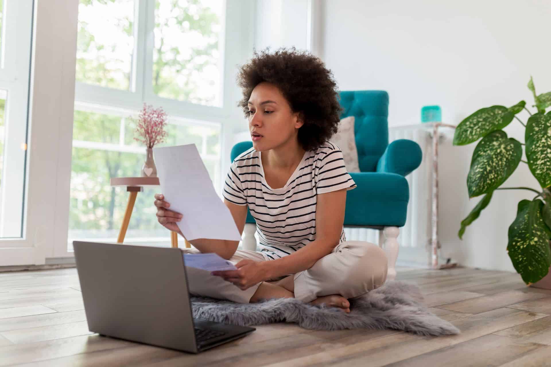 lady working at home looking at paperwork and a laptop